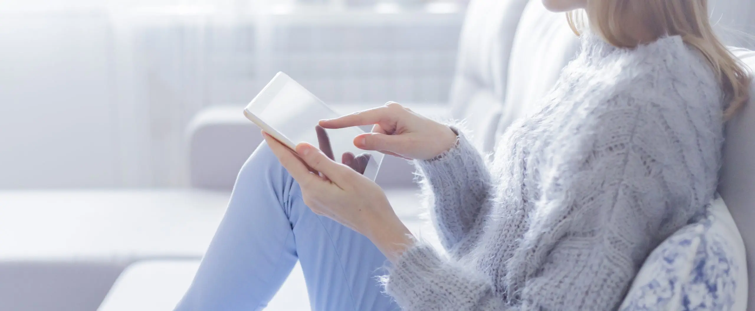 Woman sitting on couch looking at tablet